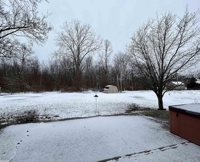 snowy yard featuring a storage unit