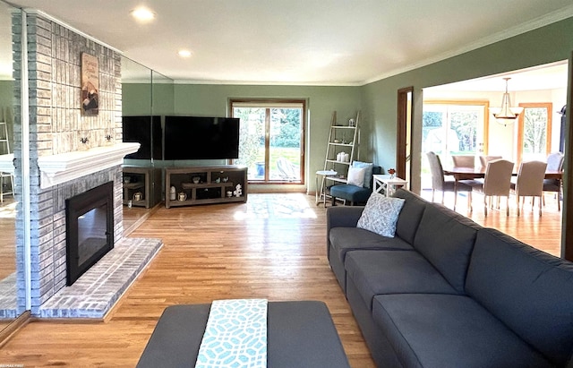 living room featuring hardwood / wood-style flooring, ornamental molding, a brick fireplace, and plenty of natural light