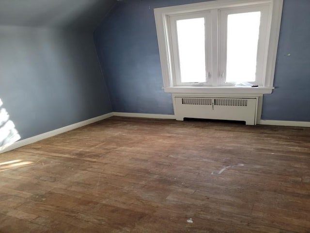 bonus room with hardwood / wood-style flooring and radiator heating unit