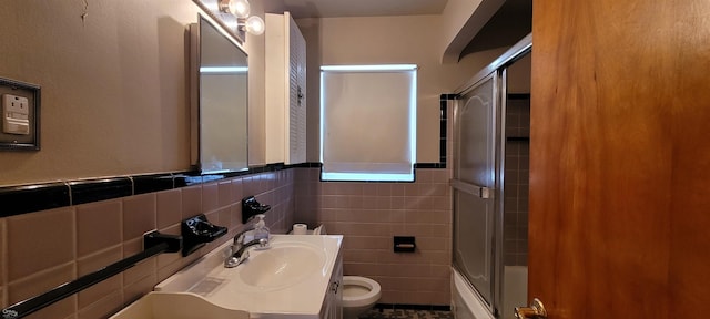 full bathroom with enclosed tub / shower combo, vanity, toilet, and tile walls