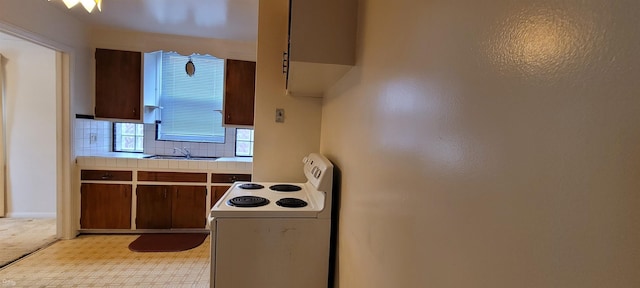 kitchen with dark brown cabinetry, white electric range, sink, and backsplash