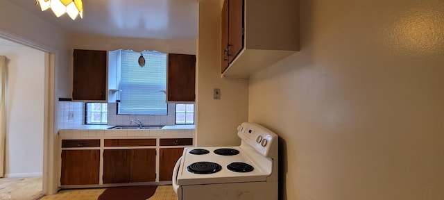 kitchen featuring tile countertops, white electric range, sink, decorative backsplash, and dark brown cabinetry