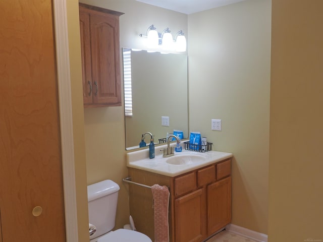 bathroom with toilet, vanity, and baseboards