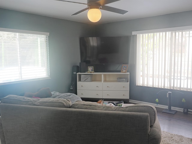 living area with a ceiling fan, baseboards, and wood finished floors