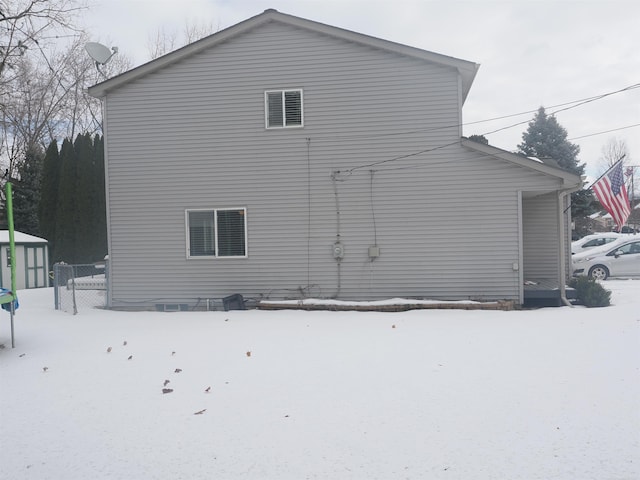 view of snowy exterior with a storage unit and an outbuilding