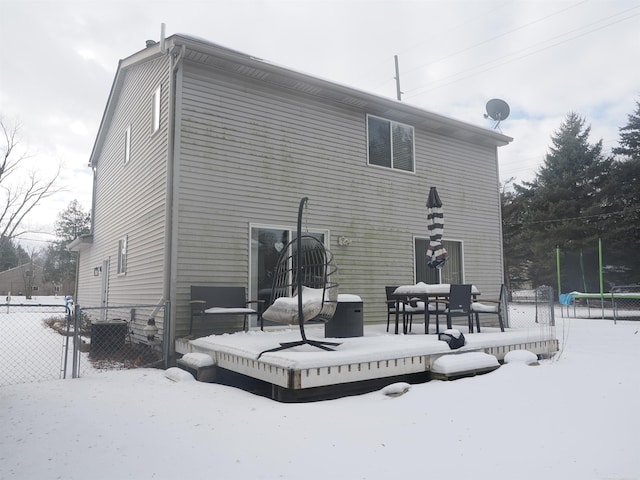 snow covered house featuring a wooden deck and fence