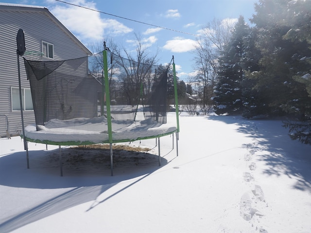 yard covered in snow featuring a trampoline