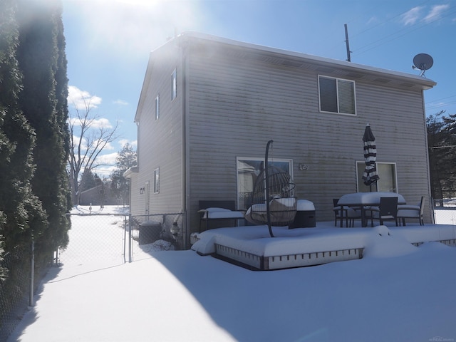 snow covered rear of property featuring a gate and fence