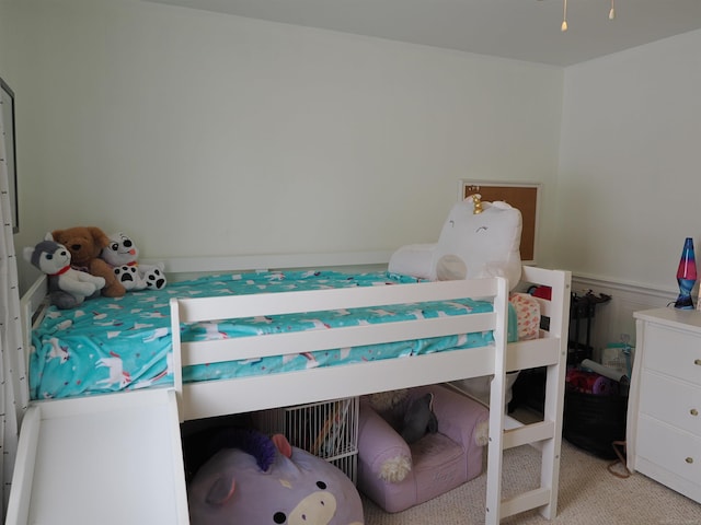 bedroom featuring light colored carpet and a wainscoted wall