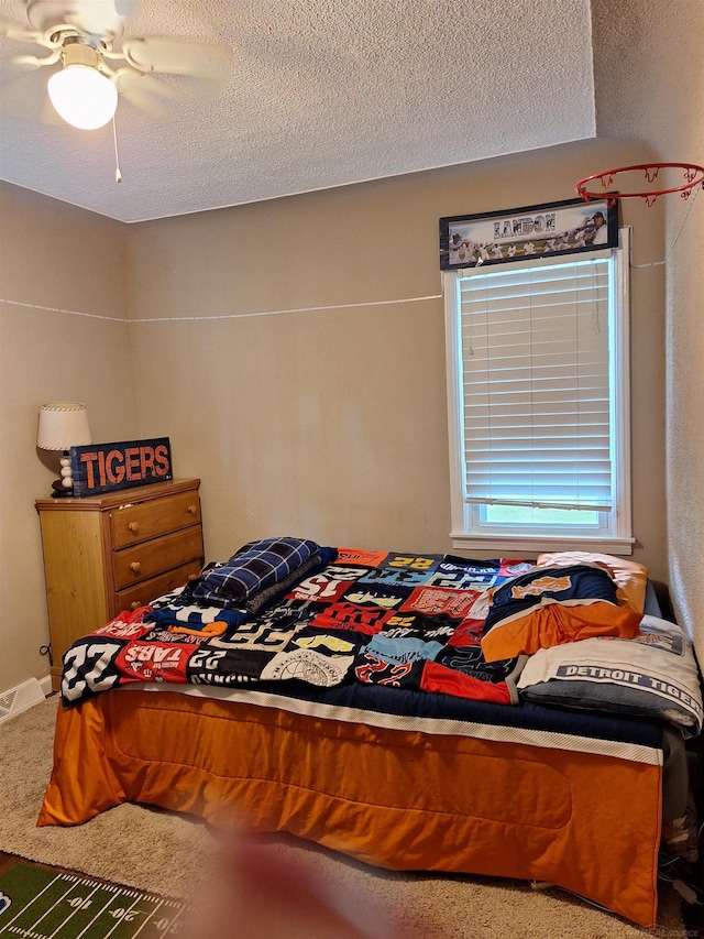 bedroom featuring ceiling fan, carpet, and a textured ceiling