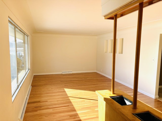 empty room featuring a baseboard radiator and light hardwood / wood-style flooring