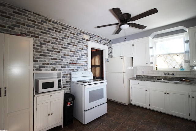 kitchen with brick wall, tasteful backsplash, white cabinetry, sink, and white appliances