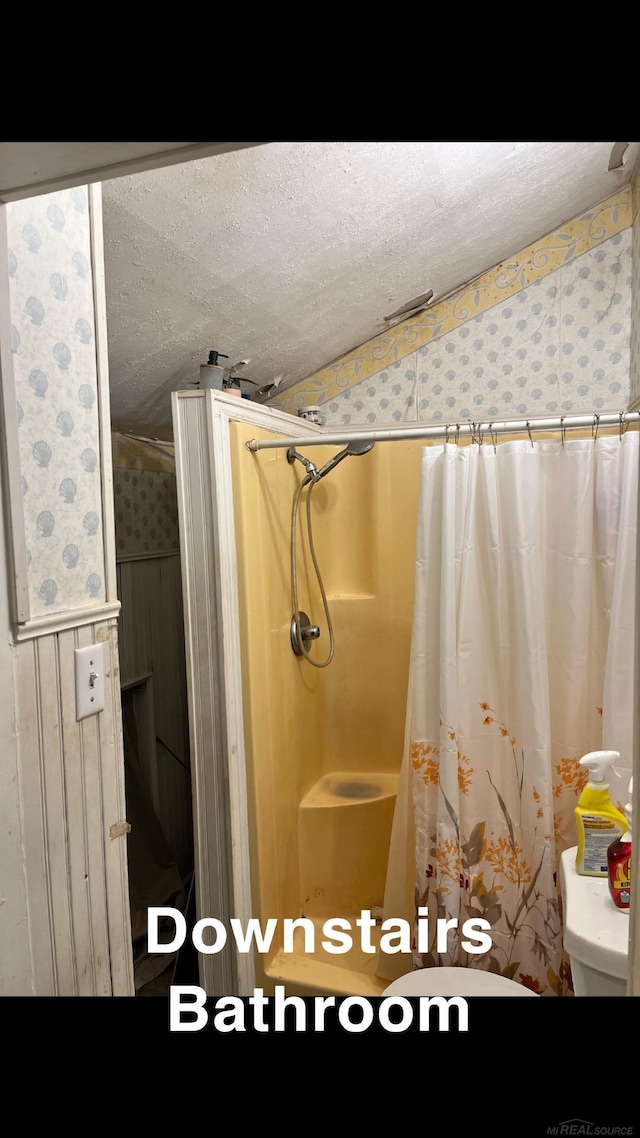 bathroom featuring toilet, a textured ceiling, and a shower with shower curtain