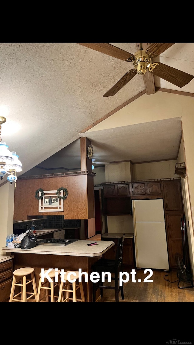 kitchen featuring vaulted ceiling with beams, hardwood / wood-style flooring, white fridge, ceiling fan, and dark brown cabinets