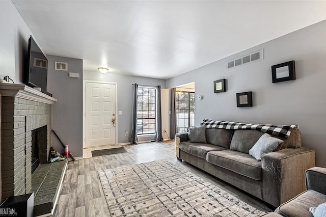 living room featuring a brick fireplace and light hardwood / wood-style flooring