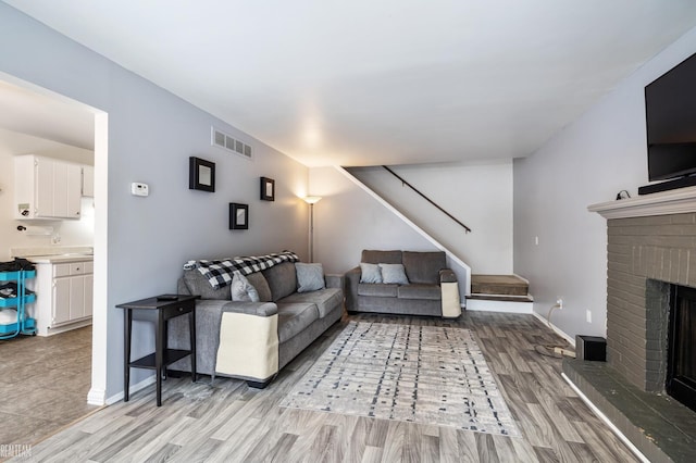 living room featuring a brick fireplace and light wood-type flooring