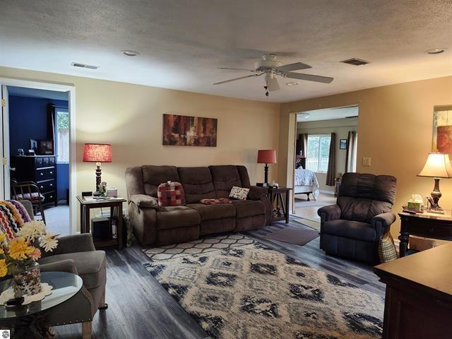 living room with ceiling fan, dark hardwood / wood-style floors, and a textured ceiling