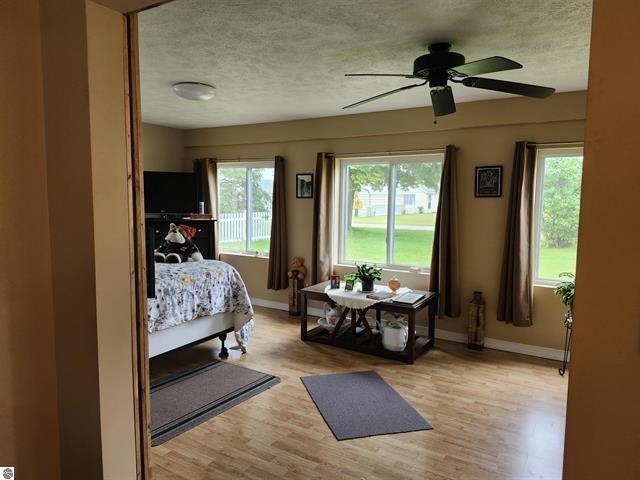 bedroom with ceiling fan, a textured ceiling, and light wood-type flooring