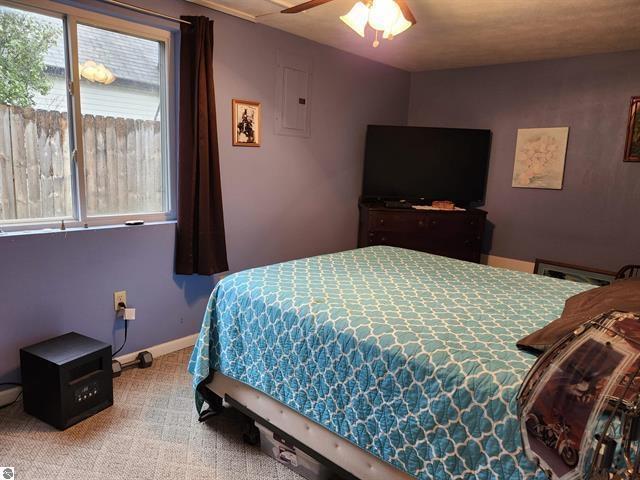 bedroom with carpet floors, electric panel, and ceiling fan