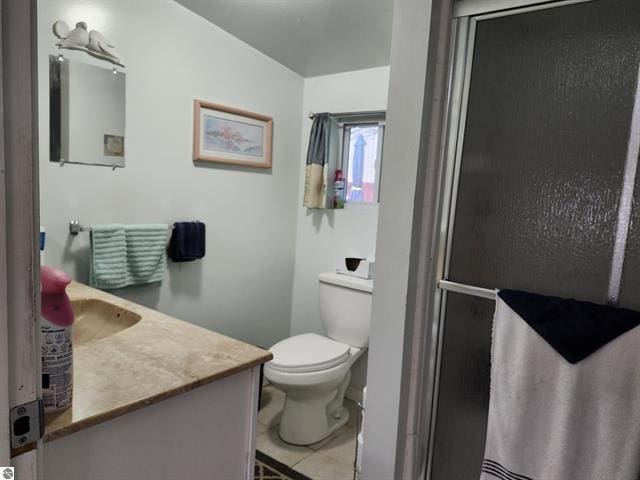 bathroom featuring tile patterned floors, vanity, toilet, and a shower with door