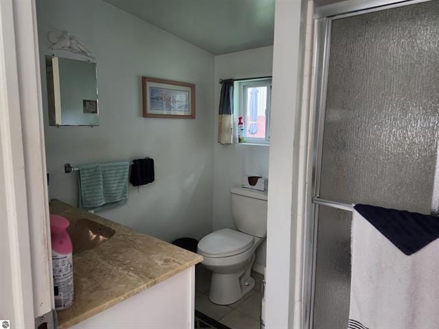 bathroom featuring vanity, toilet, a shower with shower door, and tile patterned flooring