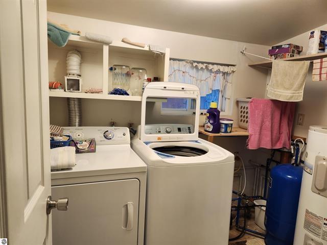 laundry room with electric water heater and washer and clothes dryer