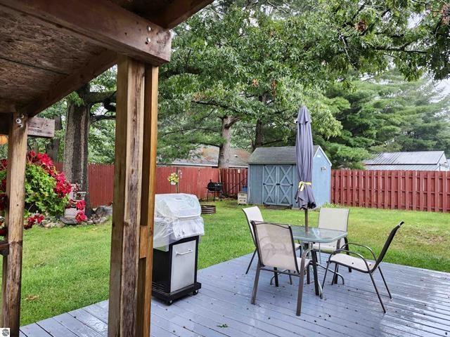 deck with a storage shed, a yard, and a grill