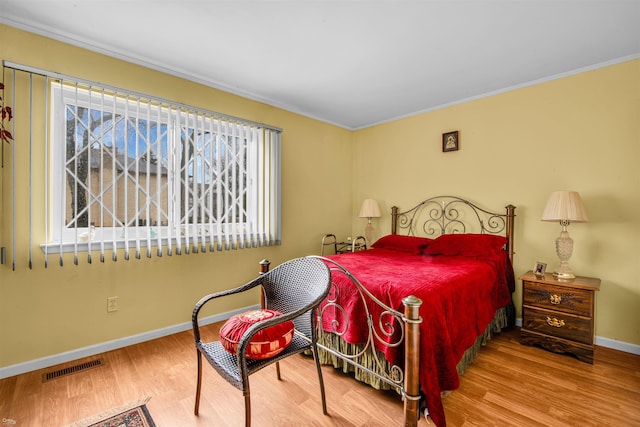 bedroom with multiple windows, hardwood / wood-style flooring, and crown molding