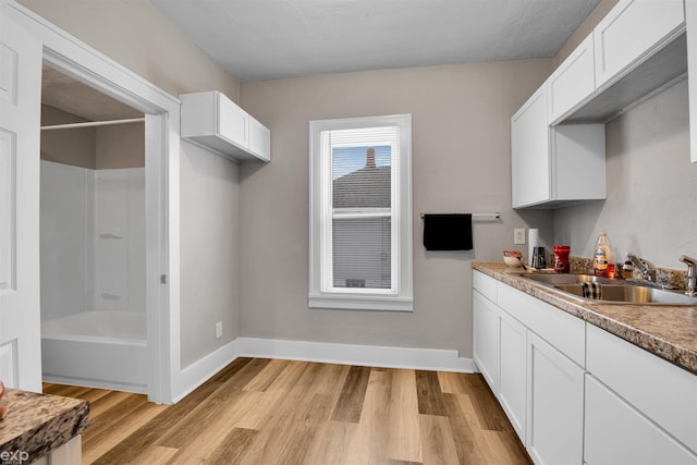 kitchen with white cabinetry, sink, and light wood-type flooring