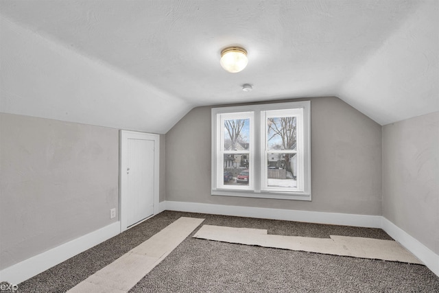 bonus room with lofted ceiling, dark carpet, and a textured ceiling