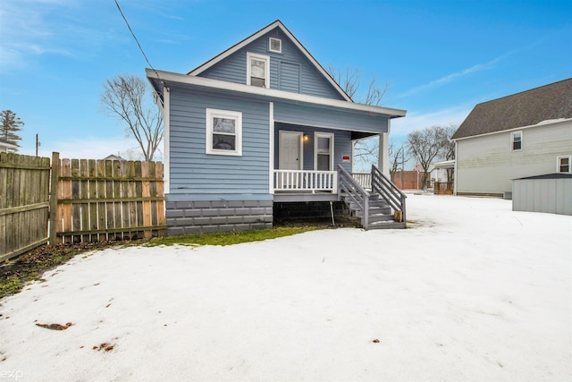 snow covered back of property with a porch