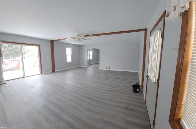 unfurnished living room featuring ceiling fan, a wealth of natural light, and wood-type flooring