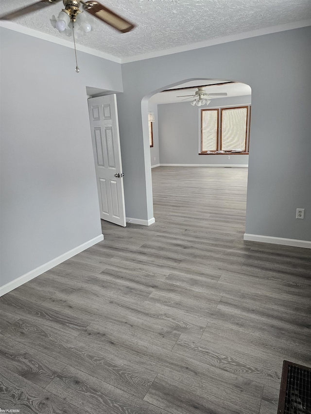 empty room featuring hardwood / wood-style flooring, ornamental molding, ceiling fan, and a textured ceiling