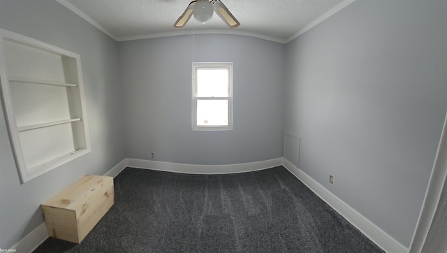 spare room with built in features, dark colored carpet, ornamental molding, ceiling fan, and a textured ceiling