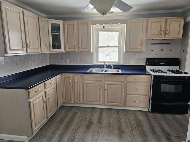 kitchen with black gas range oven, sink, ceiling fan, dark hardwood / wood-style flooring, and decorative backsplash