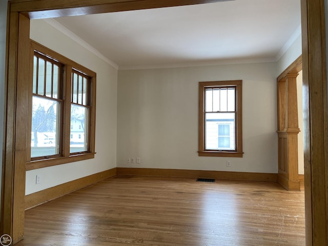 spare room with crown molding, a wealth of natural light, and light hardwood / wood-style floors