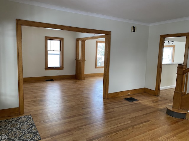 spare room with crown molding, wood-type flooring, and plenty of natural light