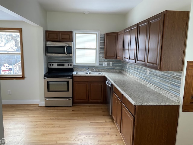 kitchen featuring stainless steel appliances, sink, light hardwood / wood-style flooring, and a wealth of natural light