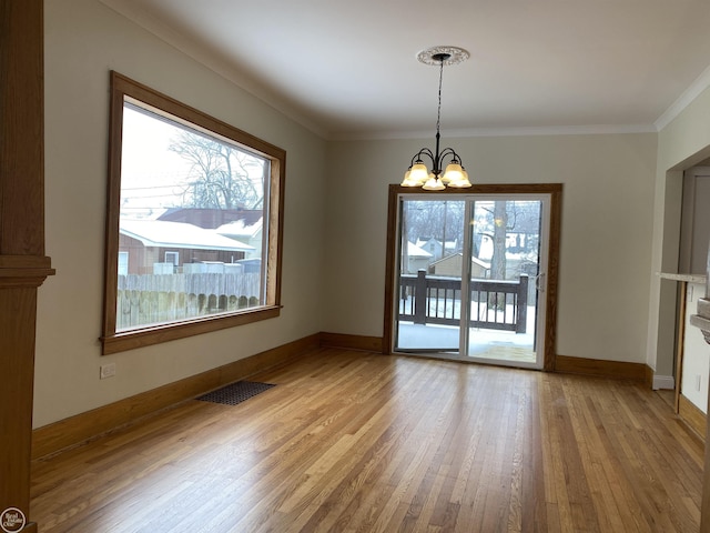 unfurnished dining area featuring an inviting chandelier, ornamental molding, and light hardwood / wood-style floors