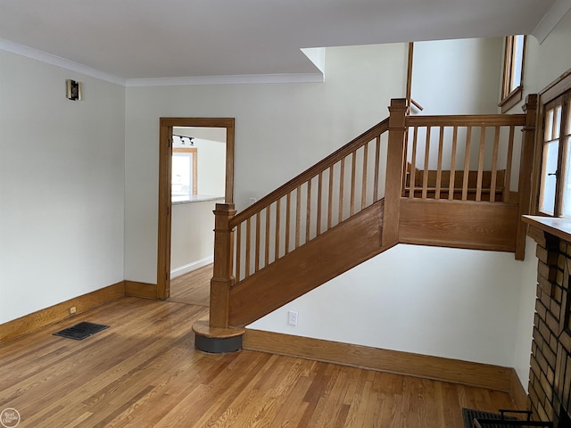 stairs with hardwood / wood-style floors and ornamental molding