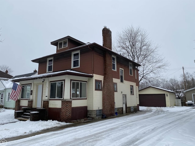 snow covered property featuring an outbuilding and a garage