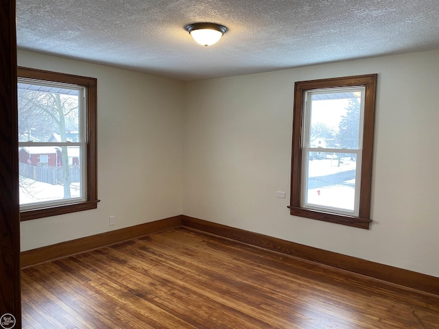 spare room with dark wood-type flooring, a wealth of natural light, and a textured ceiling