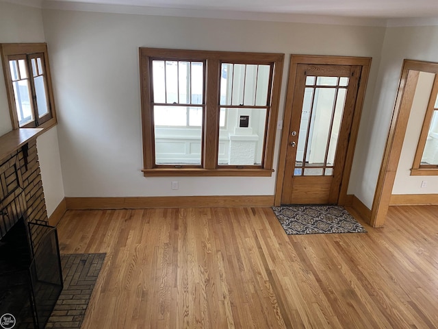 foyer entrance with a fireplace and light wood-type flooring