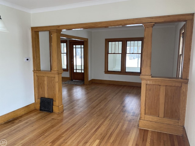 spare room with ornate columns, wood-type flooring, and crown molding