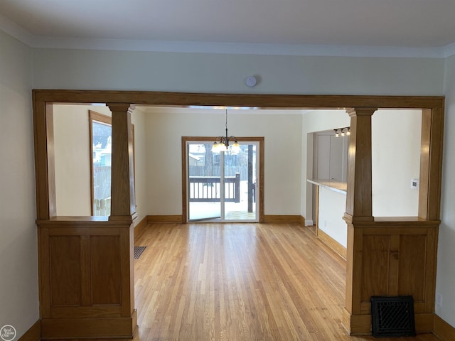 unfurnished living room with a notable chandelier, ornamental molding, and light hardwood / wood-style floors