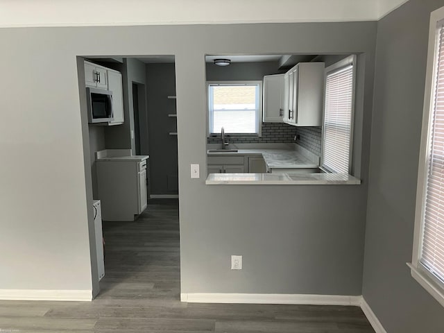 kitchen with white cabinetry, sink, decorative backsplash, and hardwood / wood-style floors