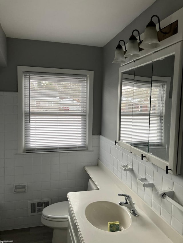 bathroom featuring vanity, tile walls, and toilet