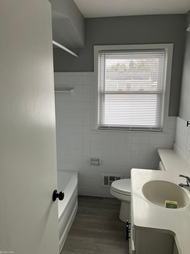 bathroom featuring vanity, hardwood / wood-style floors, tile walls, and toilet