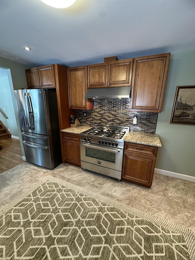 kitchen featuring decorative backsplash, light stone countertops, and appliances with stainless steel finishes