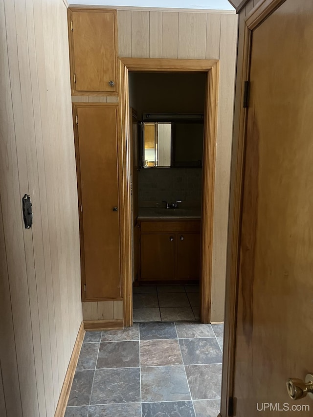 hallway featuring sink and wood walls